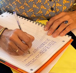 Élève pratiquant l'écriture intuitive dans un carnet lors d'une formation de médiumnité, mains posées sur un cahier à spirale